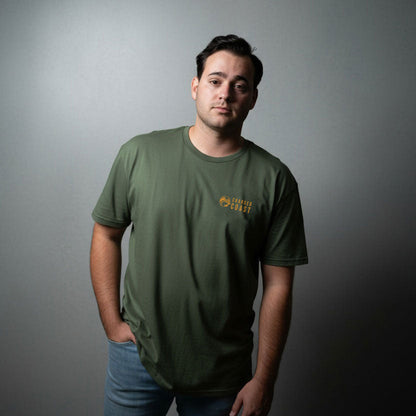 Man wearing a green charged coast brand t-shirt with a logo against a gray background